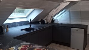 Una cocina moderna con tragaluz, muebles oscuros y un refrigerador.