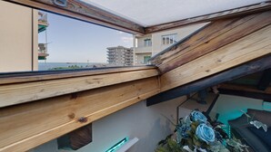 Una habitación con techo inclinado, vistas al mar y estructura de vigas de madera.
