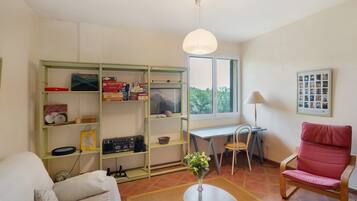 A room with a bed, a desk, a chair, a bookshelf, a lamp, and a window.