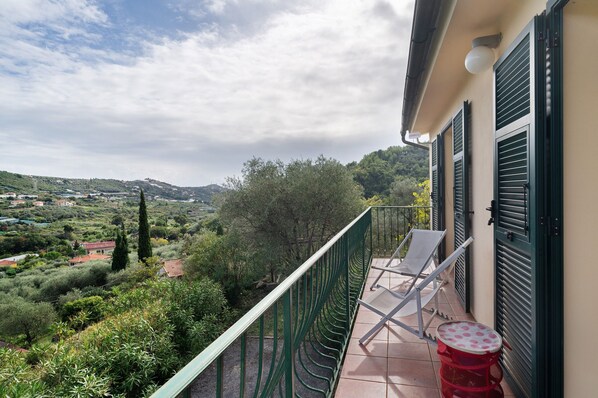 A balcony with a view of a hilly landscape, a chair, and a small table. - Holiday Home 'Casa Bilger' with Sea View, Private Terrace and Wi-Fi (Dolcedo)
