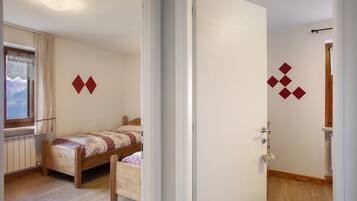 Een slaapkamer met een houten bed, een radiator en een raam met gordijnen.