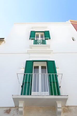 A building with white walls, green shutters, and a balcony with a metal railing. - Apartment 'Alcova' with Balcony, Wi-Fi and Air Conditioning (Fasano)
