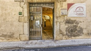 A building entrance with a wrought iron gate, a staircase leading inside, and a signboard for Can Gibern. - Apartment 'Apartaments Can Gibert - Aiguamolls' with Private Terrace, Wi-Fi and Air Conditioning (Castelló d'Empúries)