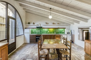 Una cocina con mesa, sillas, una lámpara colgante y un salpicadero verde.