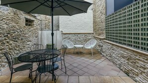 An outdoor patio with a round table, chairs, and a large umbrella.