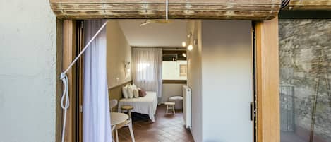 A room with a bed, a small table, a chair, and a round green ottoman.