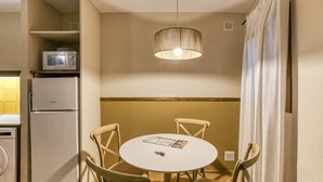 A compact kitchen with a microwave, refrigerator, and dining table with chairs.