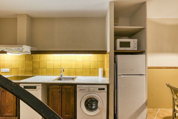 Una cocina compacta equipada con lavavajillas, lavadora, microondas y un refrigerador pequeño.