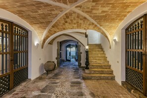 Un pasillo con suelo de piedra, techos abovedados y puertas de madera.
