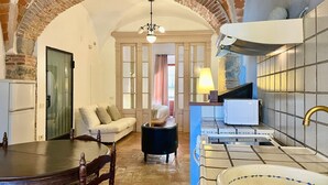 Una habitación con una mesa de comedor, un sofá, un reposapiés negro, una cama con vistas, una lámpara, un microondas y un salpicadero de azulejos.