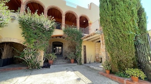 A courtyard with arches, potted plants, and a stone wall.