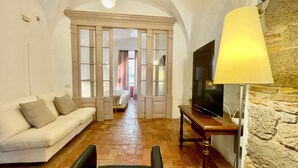 Una habitación con sofá, televisión sobre un mueble bajo, lámpara y pared de piedra.