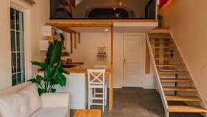 Un espace de vie de style industriel, avec un canapé, une table basse en bois et un escalier menant à une mezzanine.