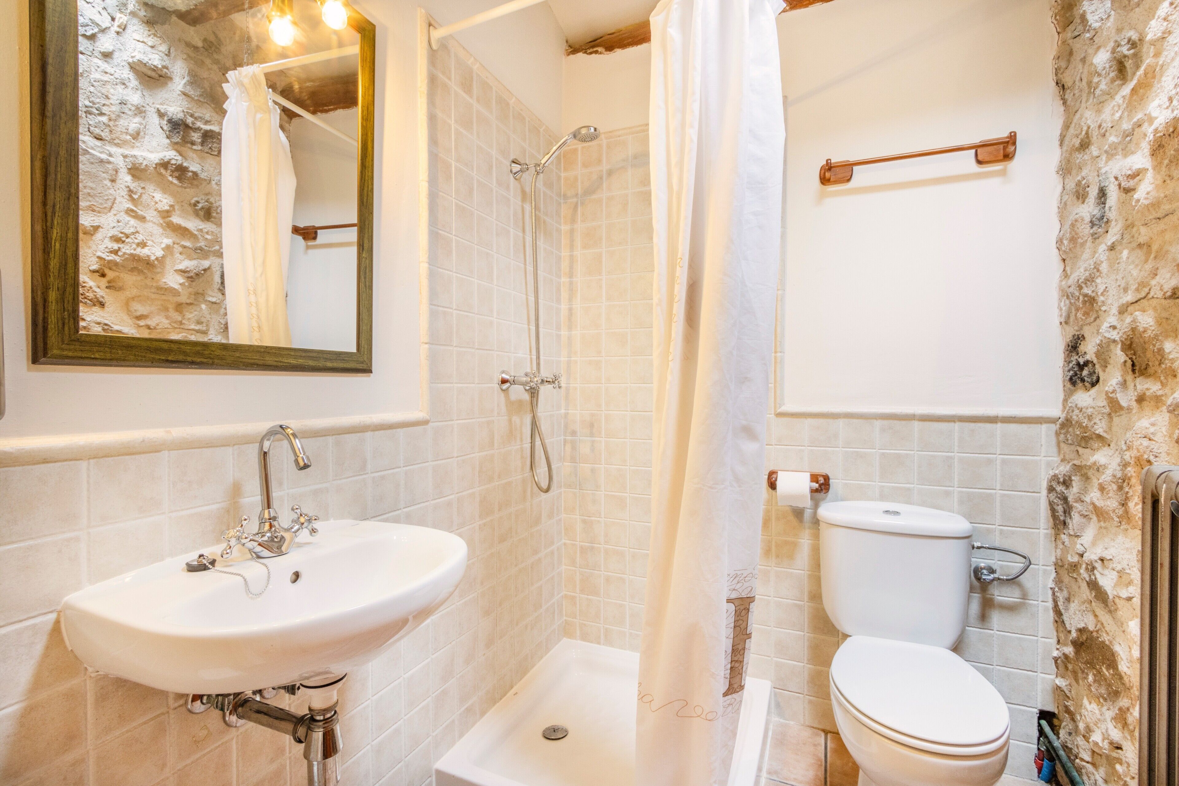 Une salle de bain équipée d’un lavabo, d’une douche, de toilettes et d’un miroir.