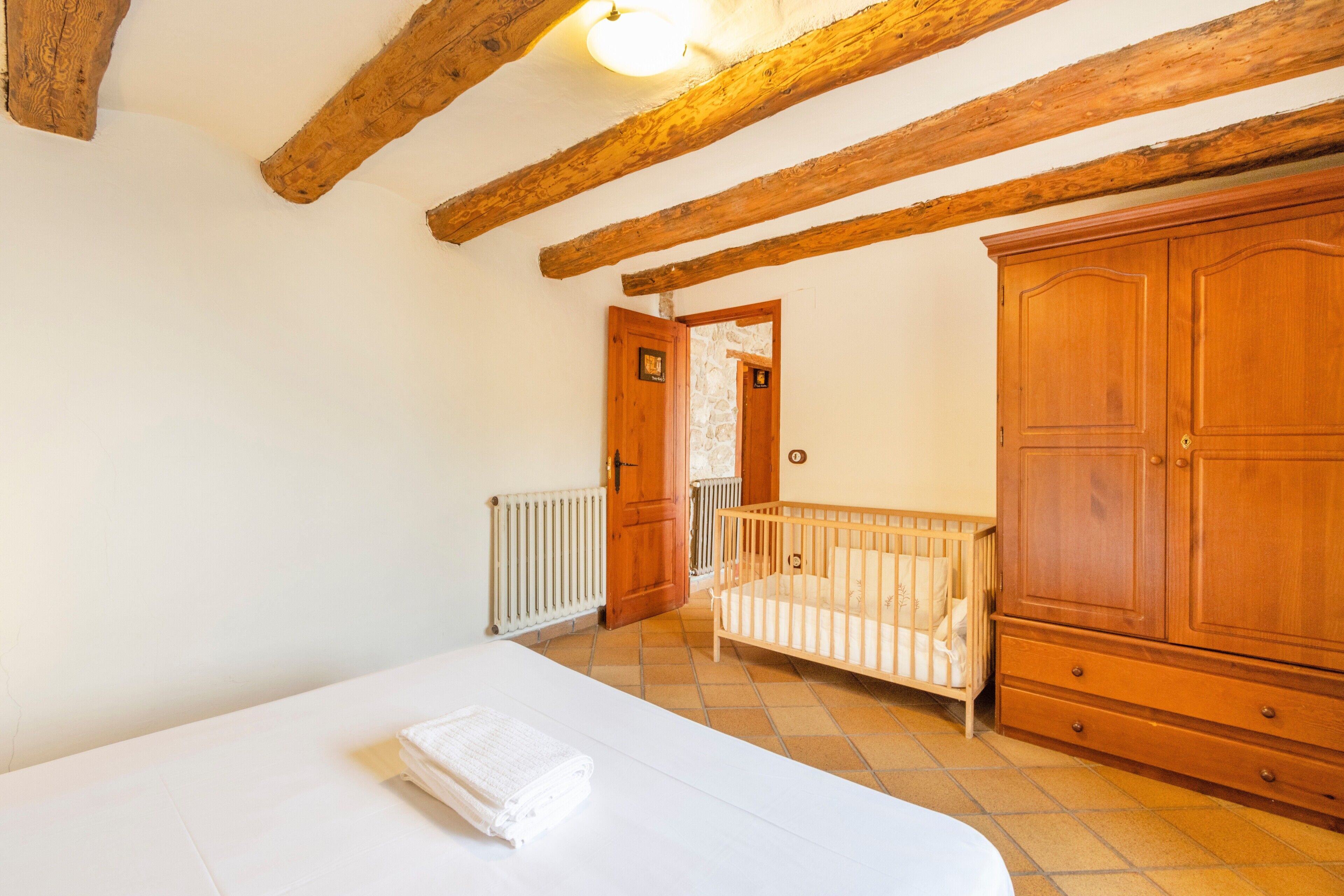 A bedroom with a bed, wooden wardrobe, and a crib.