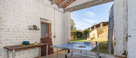 A ping pong table in a room with white brick walls, a door, and a window.