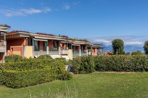 A row of two-story buildings with balconies, a well-maintained lawn, and a clear view of distant mountains.