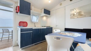 Een compacte keuken met een eethoek, een raam met uitzicht, en een brandblusser op het aanrecht.
