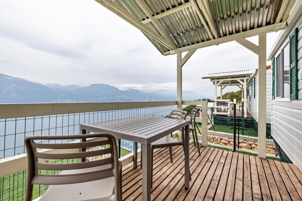 A wooden deck with a table and chairs, overlooking a mountainous landscape.