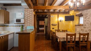 Una cocina con armarios de madera, un microondas y un comedor con mesa y sillas.