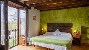 Un dormitorio con cama, cabecera de madera, paredes verdes y un balcón.