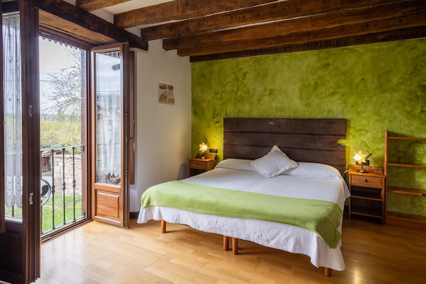 A bedroom with a bed, wooden headboard, green walls, and a balcony.