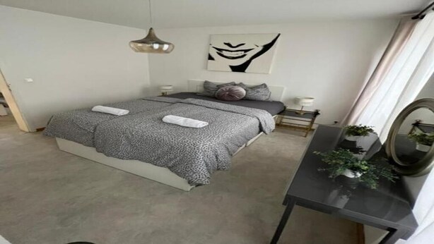 Un dormitorio moderno con cama, mesitas de noche, un escritorio y un espejo.