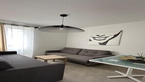 Una sala moderna con un sofá gris, una mesa de centro de madera y una mesa de comedor con tapa de vidrio.