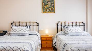 Una stanza con due letti, un comodino con una lampada e un quadro appeso al muro.