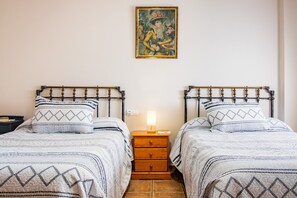 A room with two beds, a nightstand with a lamp, and a painting on the wall. - Country House 'Casa Rural Arroal I' with Mountain View, Wi-Fi and Air Conditioning (Sotoserrano)