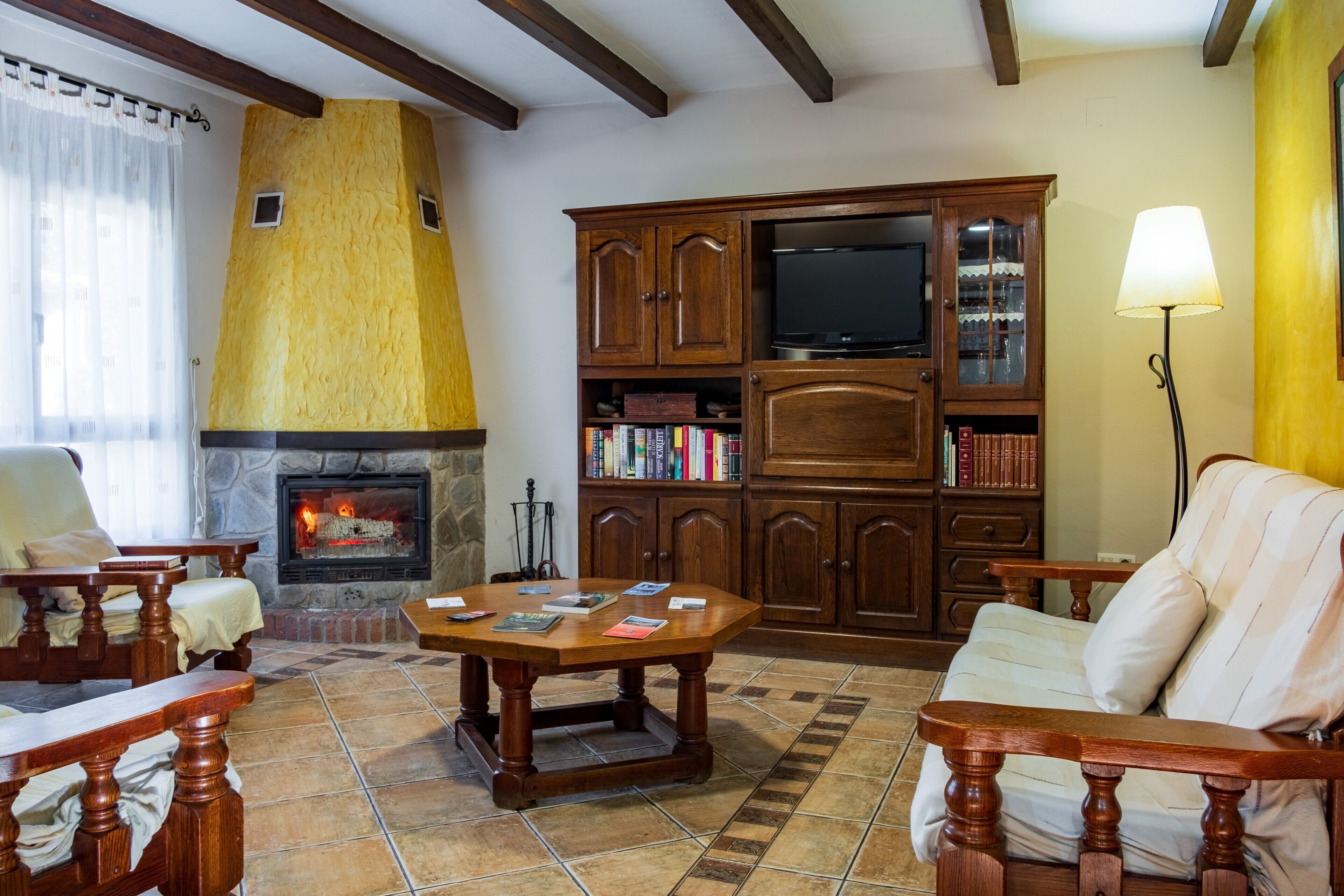 Un salon avec une cheminée, des meubles en bois, un téléviseur et des étagères à livres.