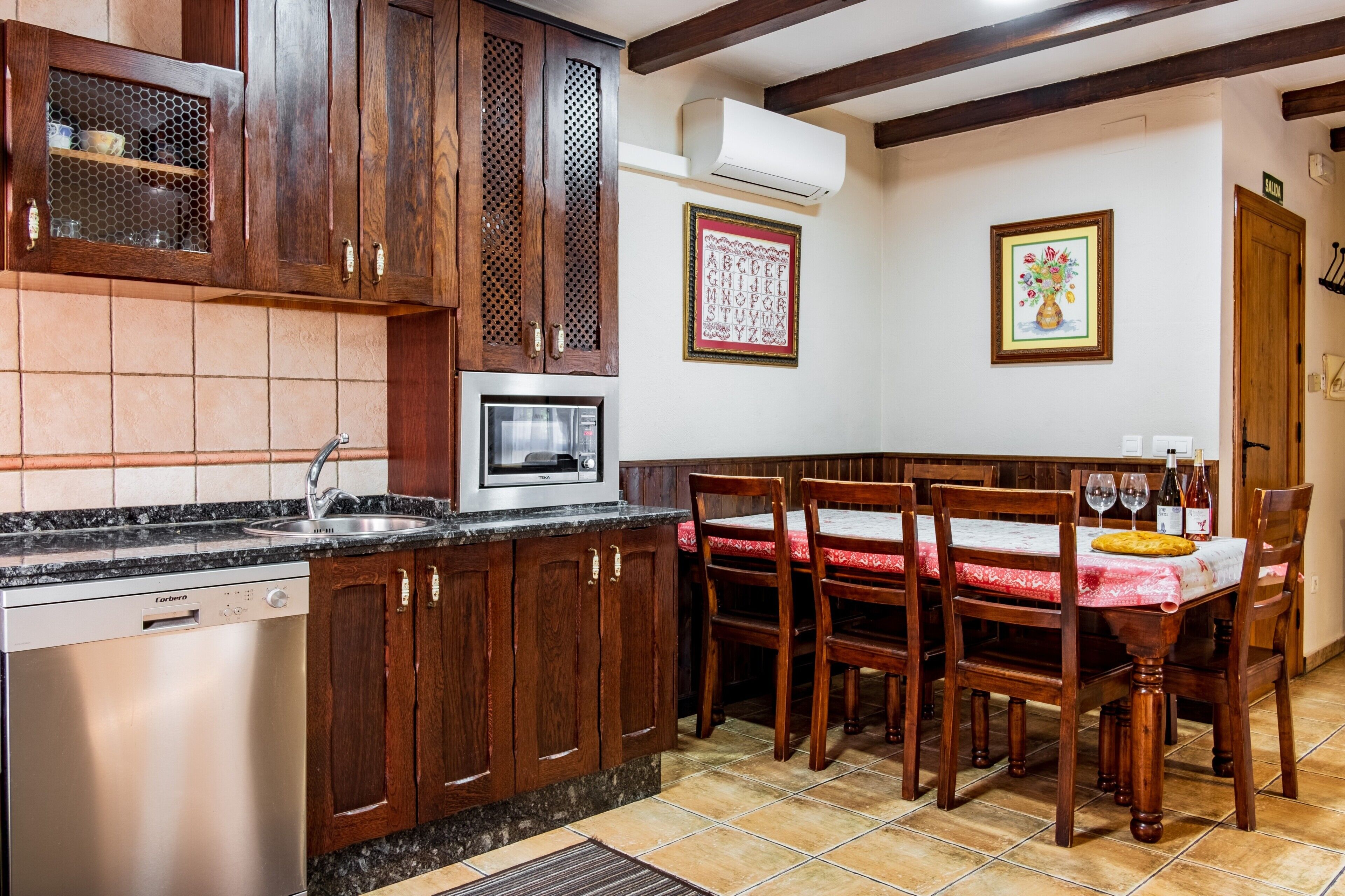 A kitchen with wooden cabinets, a built-in microwave, a sink, and a dining area with a table and chairs.