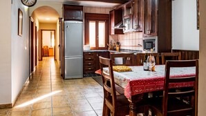 Une cuisine avec des meubles de rangement en bois, un réfrigérateur et une table à manger avec des chaises.