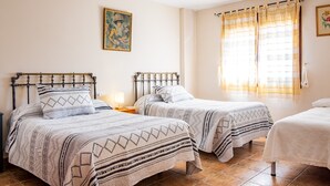 Une chambre avec deux lits, une table de chevet, un tableau et une fenêtre avec des rideaux.