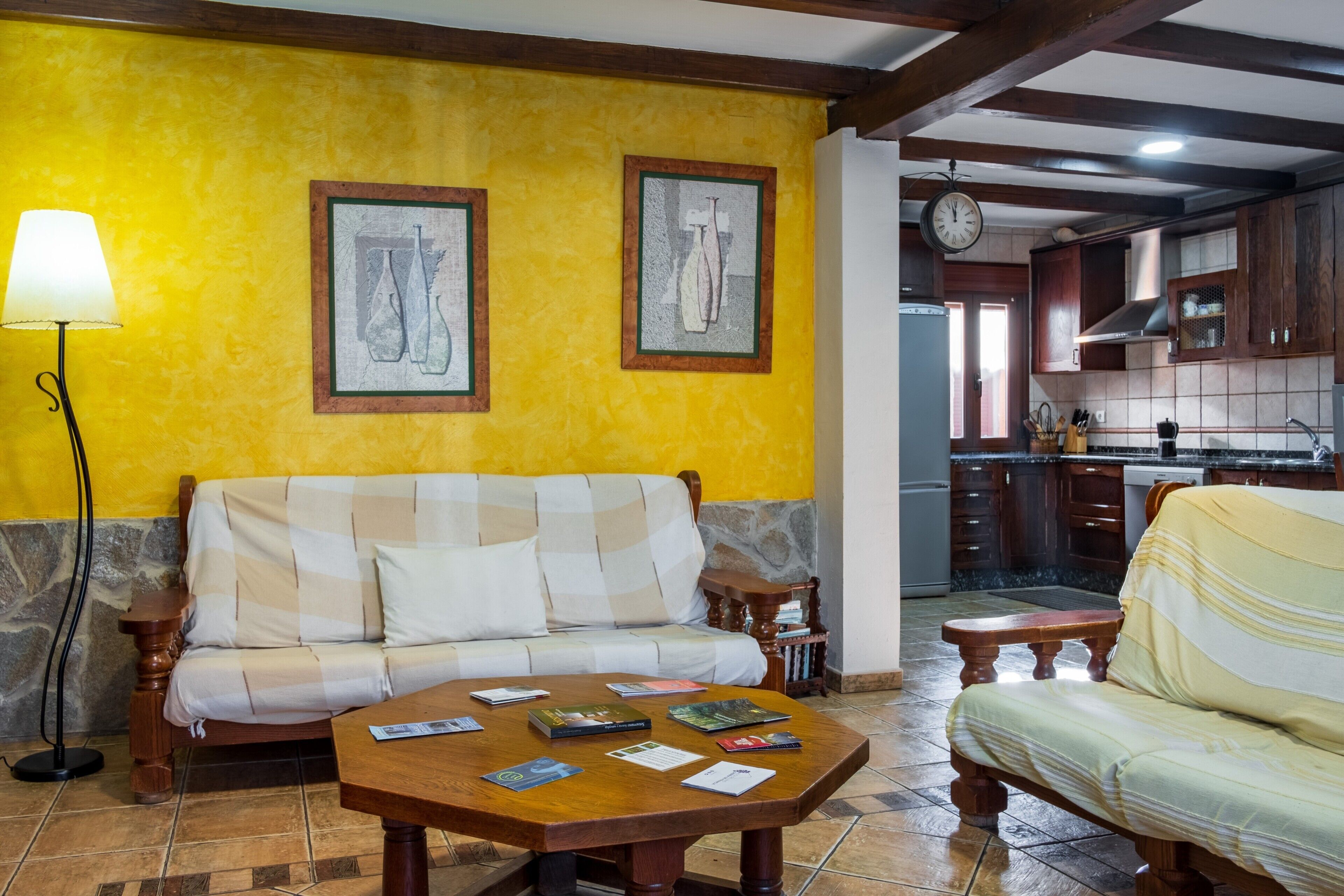 A living room with a sofa, a coffee table with books, a lamp, and framed artwork on the wall.