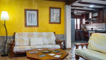 A living room with a sofa, a coffee table with books, a lamp, and framed artwork on the wall.