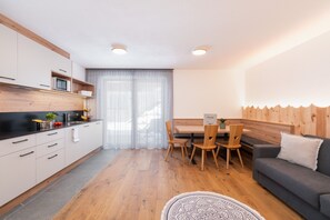 Una cocina moderna con armarios de madera, un comedor con mesa y sillas, y un sofá en la sala de estar.