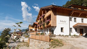 Un bâtiment en bois doté de balcons, d’un mur en pierre et d’une enseigne sur laquelle on peut lire « Huberhof ».