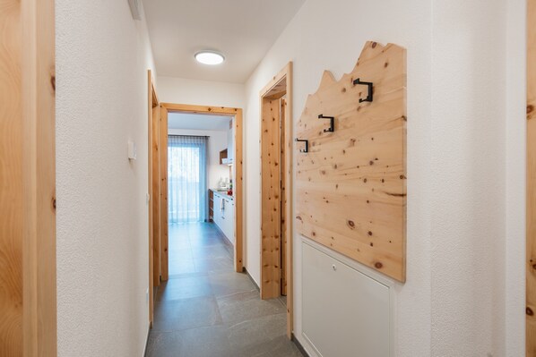 A hallway with wooden doors, a wooden wall panel, and a tiled floor.