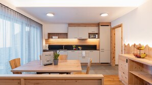 Une cuisine moderne avec des meubles en bois, une table à manger et un four à micro-ondes encastré.