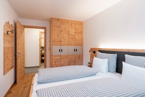 Un dormitorio con un armario de madera, una cama con ropa de cama a cuadros y un cabecero.