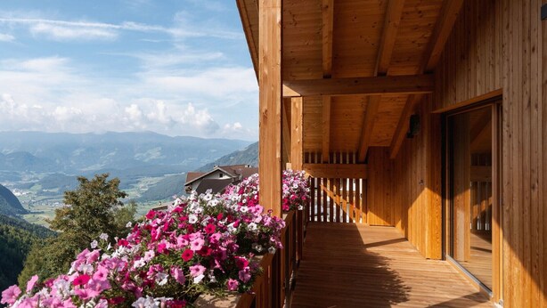 Une cabane en bois dotée d’un balcon donnant sur un paysage montagneux.