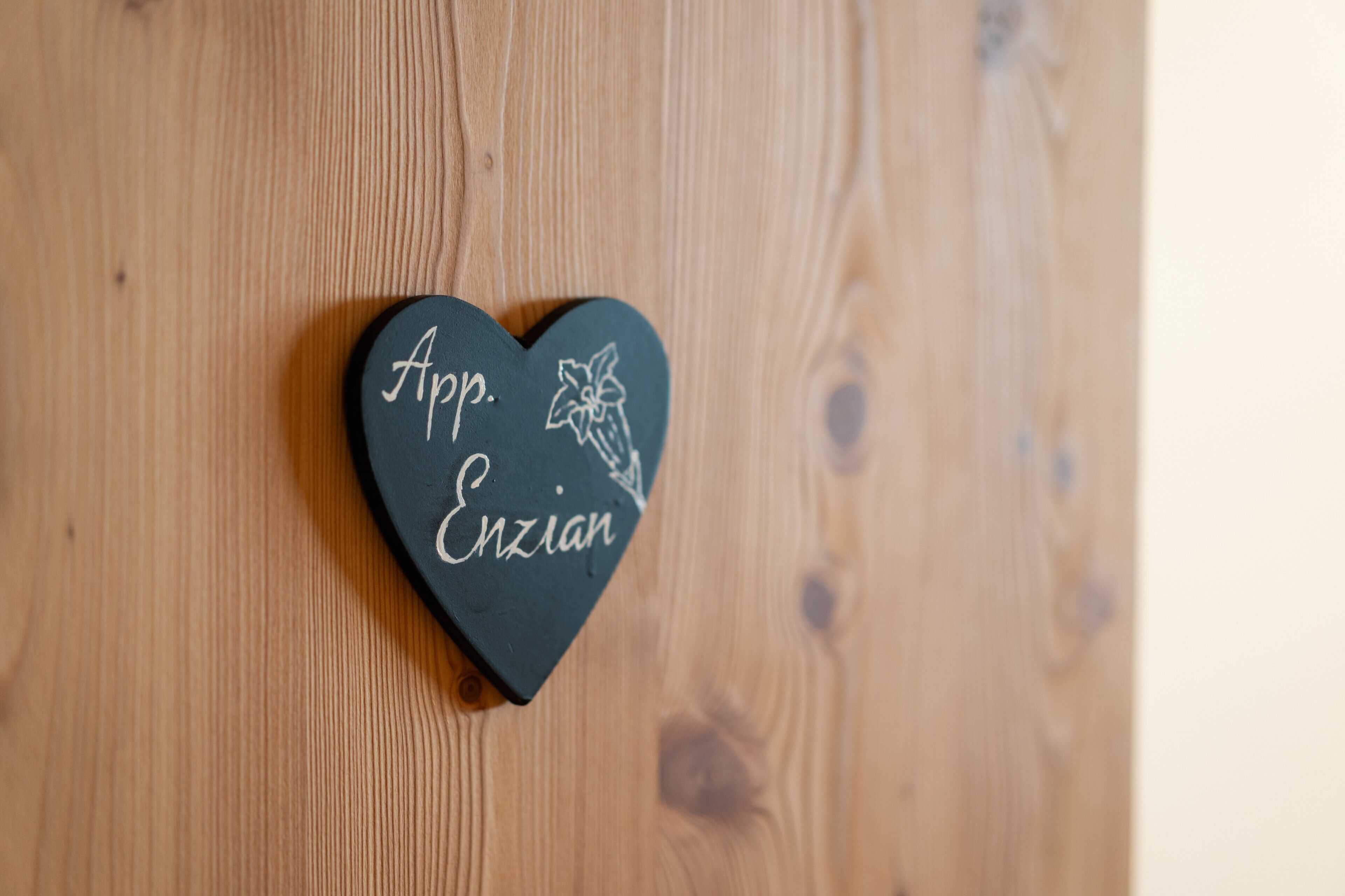 A heart-shaped object with the text 'App. Enzian' on a wooden surface.