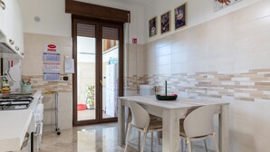Una cocina con estufa, una mesa con sillas, un calendario y una puerta que da al exterior.