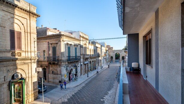 Una calle estrecha con edificios históricos, un teléfono público a la vista y un cielo despejado.