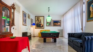 Una mesa de billar, un sofá, un mantel rojo y un reloj sobre un aparador.
