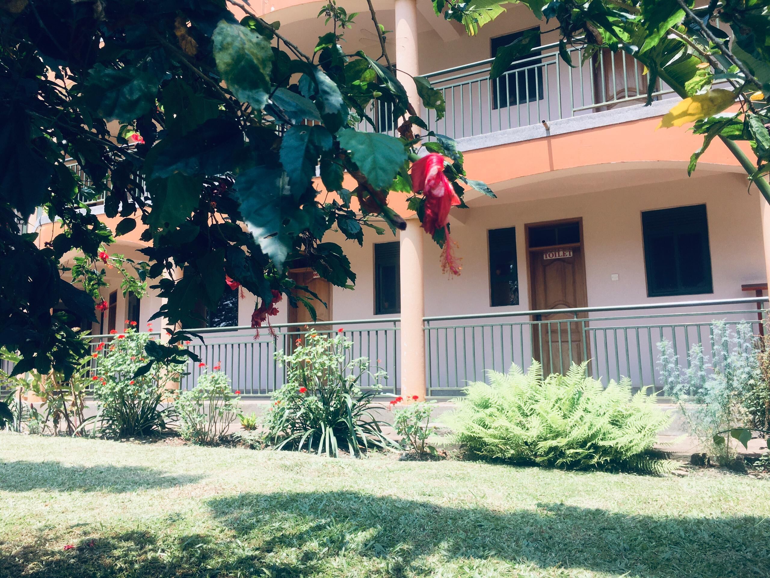 A building with a balcony, a sign indicating a toilet, and various plants.