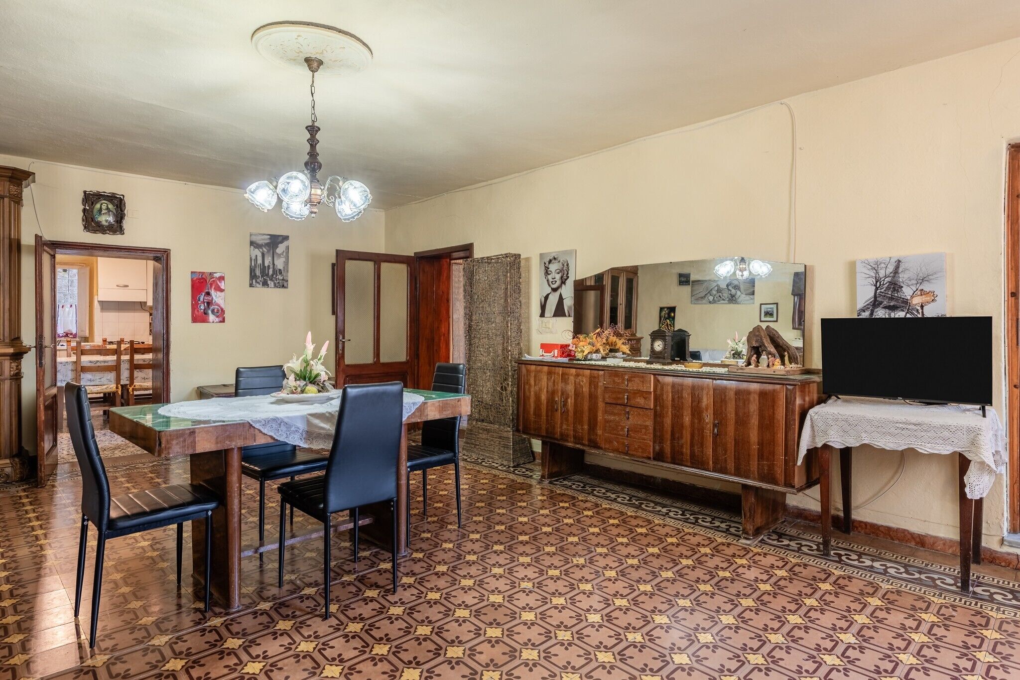 A dining area with a table set for four, a wooden cabinet, and a television on a stand.