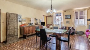 Ein Essbereich mit Holztisch, Stühlen, einer Chandelier und einem gemusterten Boden.