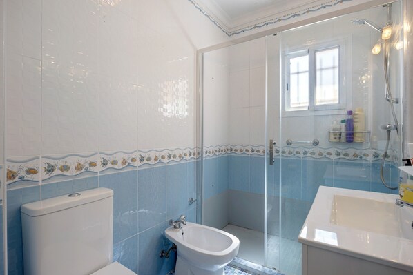 A bathroom with a toilet, bidet, and shower area.